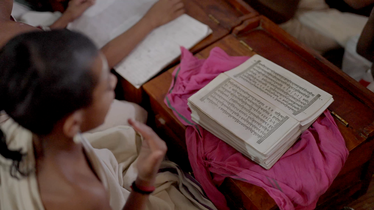 Home A young student is studying a religious text in a traditional classroom setting, focused and engaged.