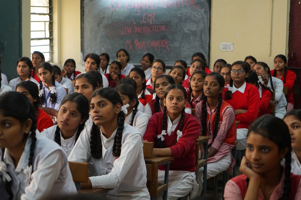 Offerings Group of Indian schoolgirls in uniform attentively listening in a classroom setting.